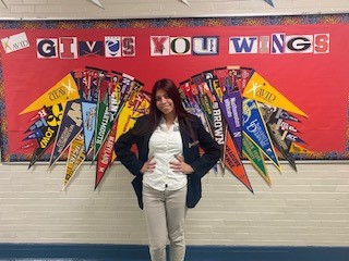 A person standing in front of a signDescription automatically generated with medium confidence